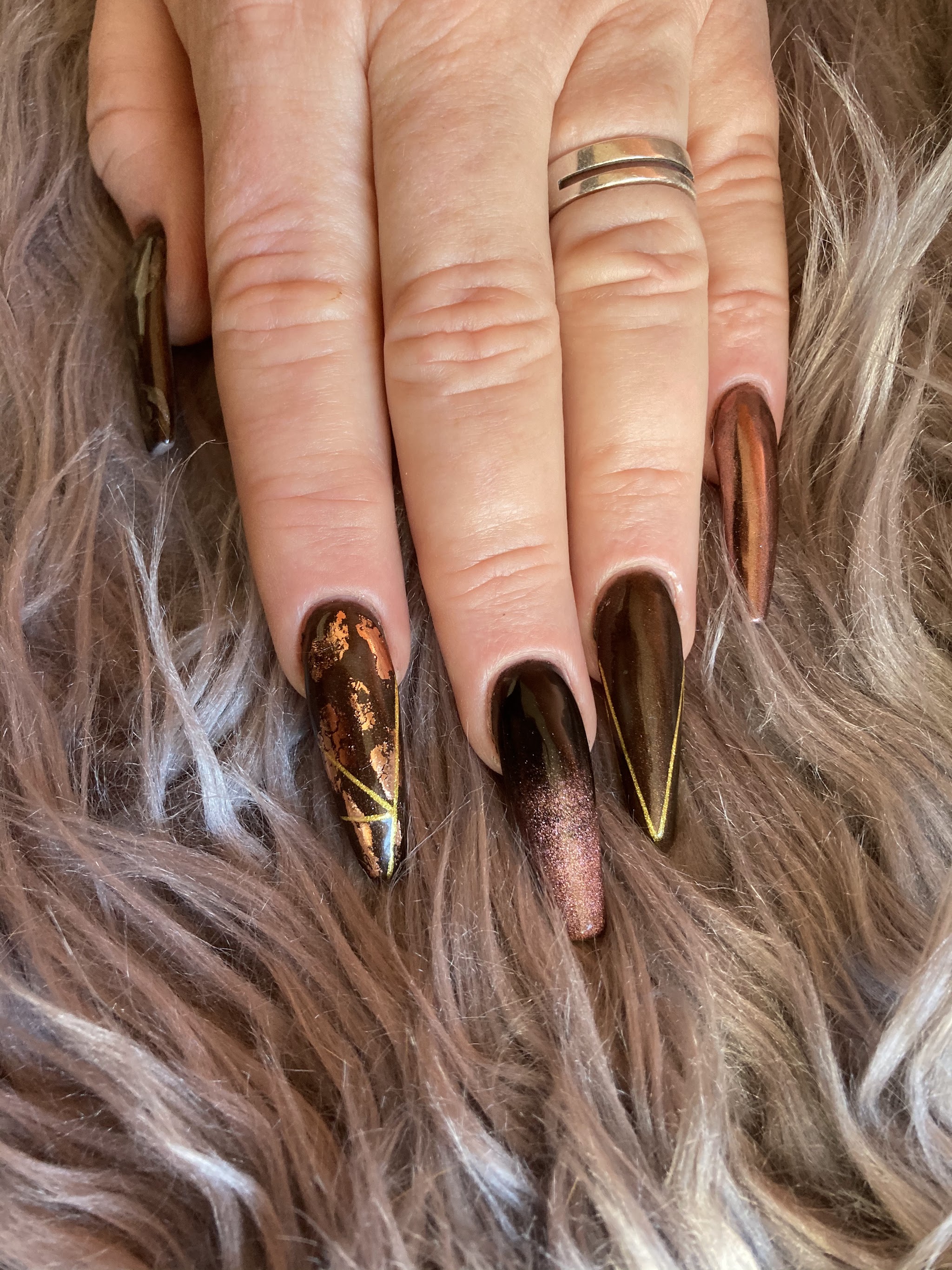 Afgewerkte lange nagels met donkere glans en gouden accenten