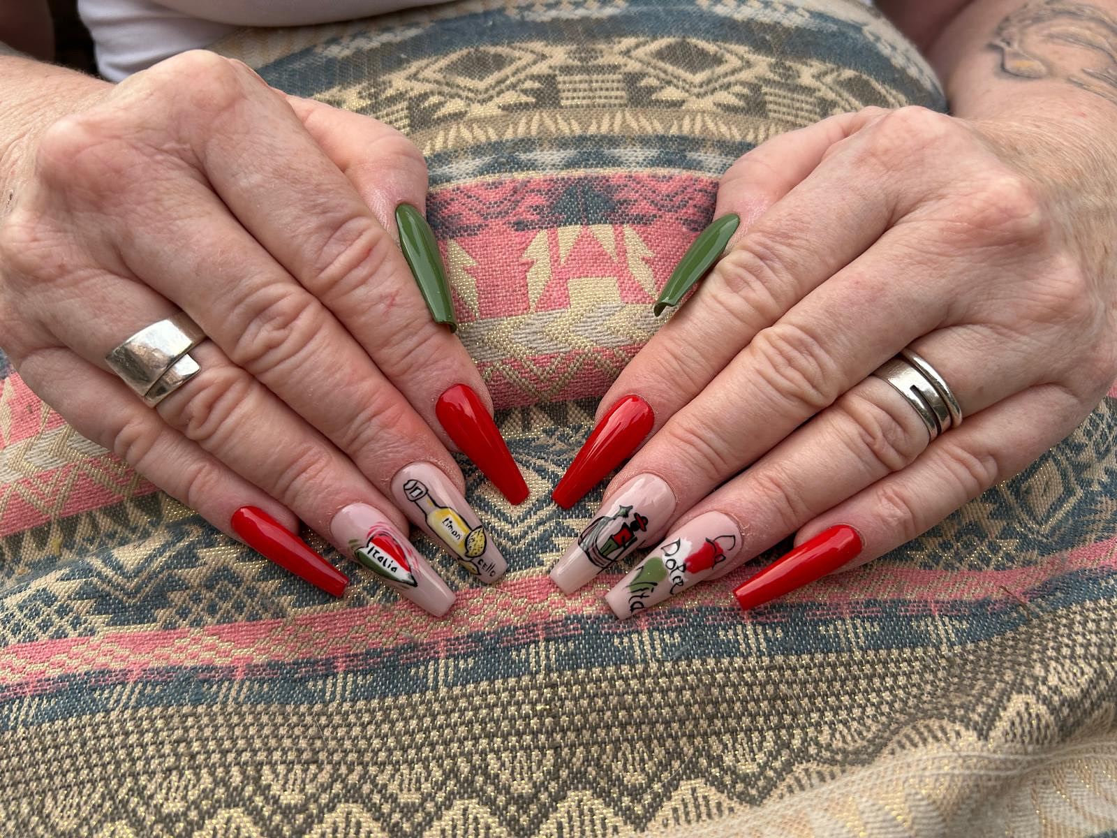Rode en groene nagels met gedetailleerde nagelkunst op twee handen
